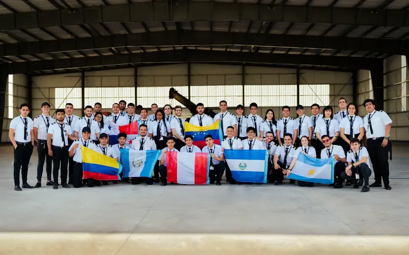Estudiantes internacionales de ProFlight con las banderas de sus países en el hangar