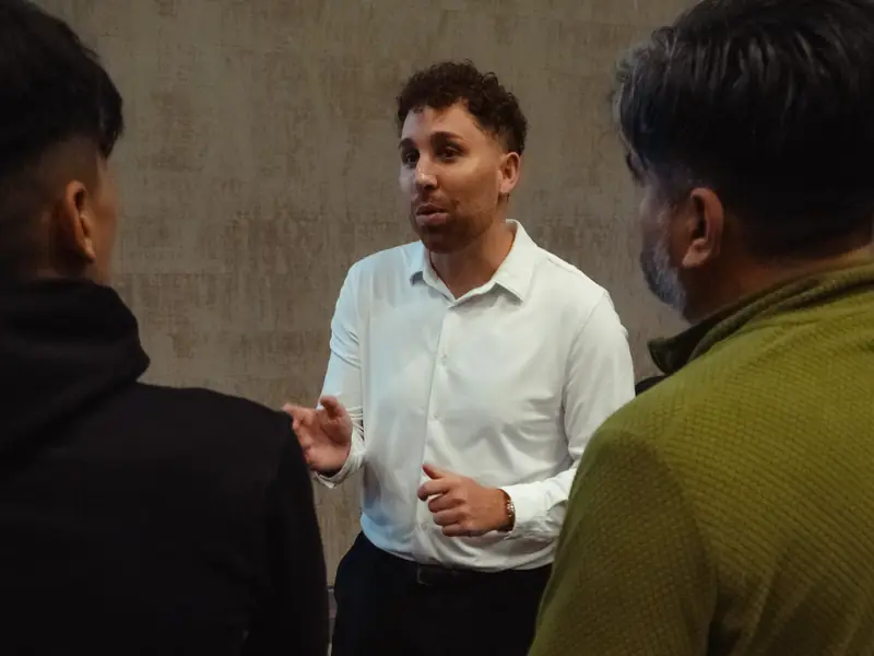 Un integrante de ProFlight Academy conversa con dos asistentes en una charla presencial