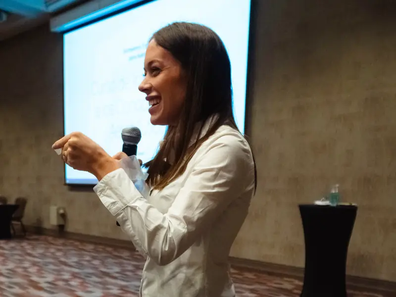 Una expositora de ProFlight Academy habla al público con el micrófono en la mano